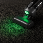 Guu Vision 2.0 handheld vacuum using green LED light to find and remove embedded pet hair from dark upholstery.
