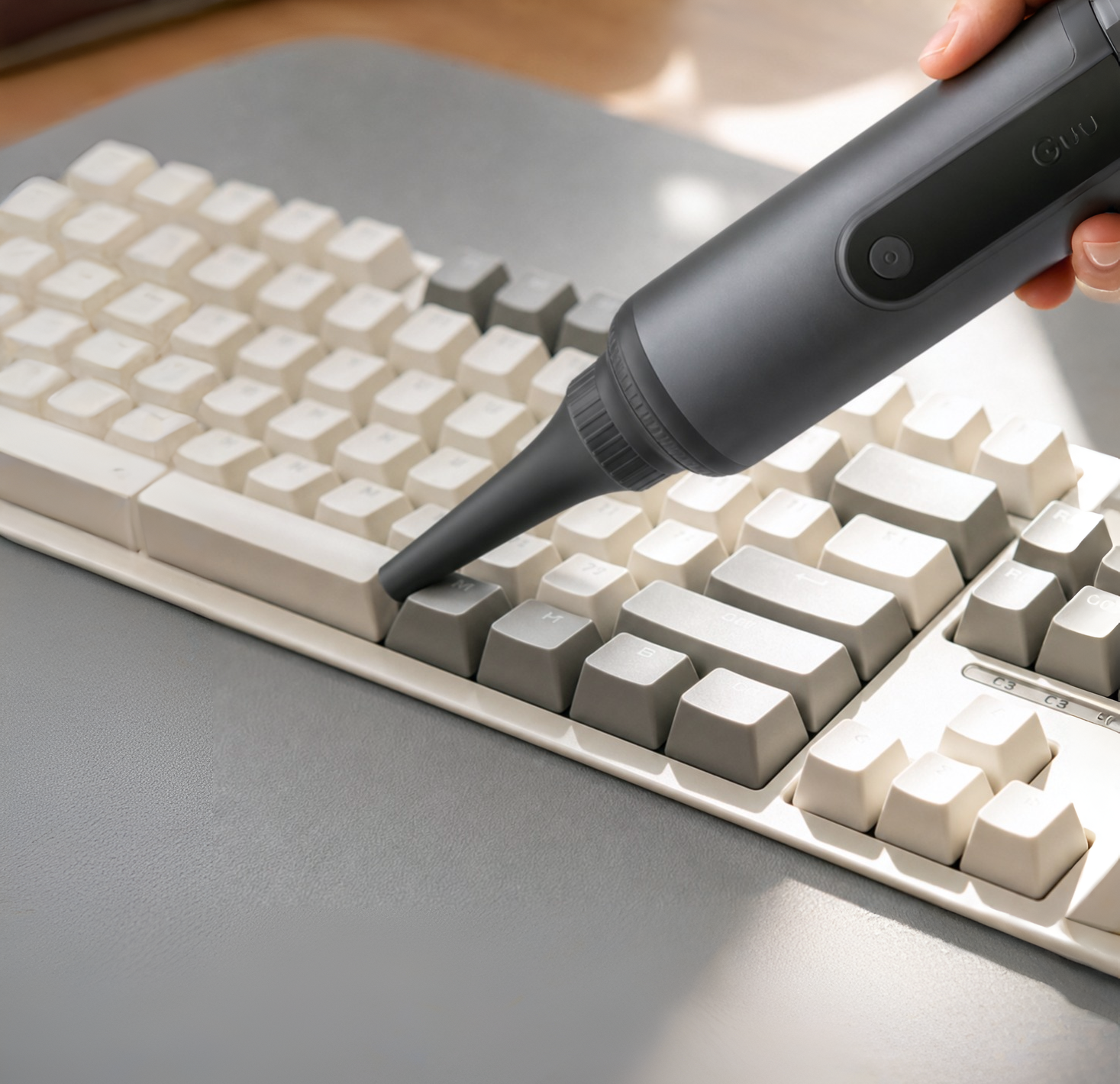 Using the blower function of the Guu 4-in-1 cordless vacuum to easily blast away trapped dust from narrow keyboard crevices.