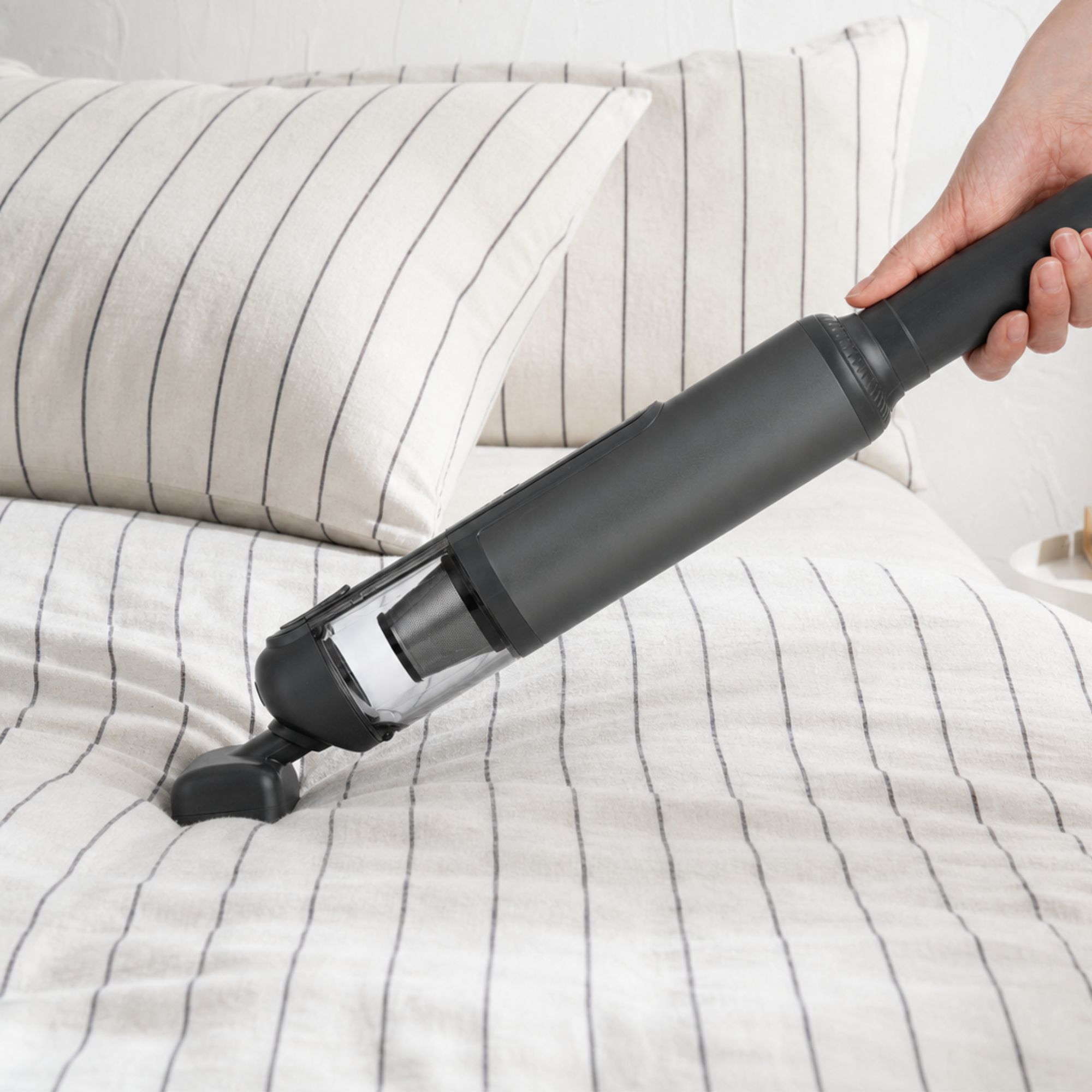 Guu Vision 2.0 handheld vacuum using powerful suction to deep clean hidden dirt and debris from bed sheets and mattresses.