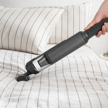Guu Vision 2.0 handheld vacuum using powerful suction to deep clean hidden dirt and debris from bed sheets and mattresses.